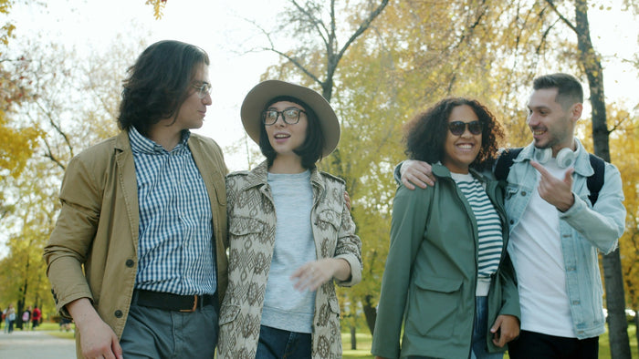 Happy young couples are walking outdoors in park on sunny autumn day talking smiling having fun. Communication, youth and modern lifestyle concept.
